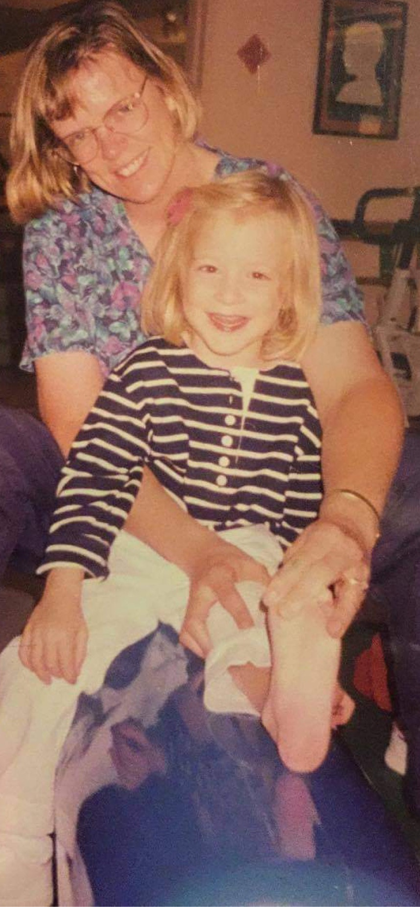 The website author at physical therapy as a child. She and her therapist are stretching her hamstrings. She is smiling.