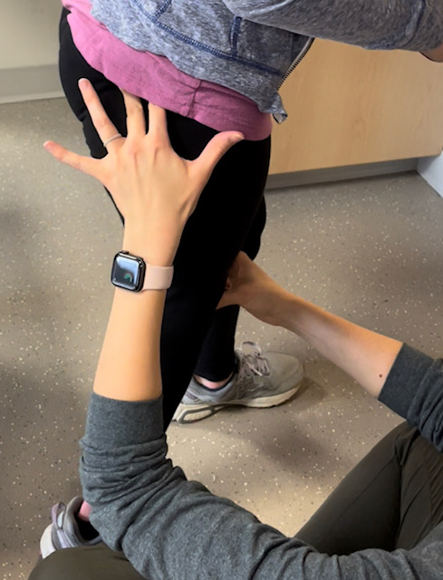 A young woman who had SDR. Her back is to the camera, and she has a scar on her lower back from SDR.